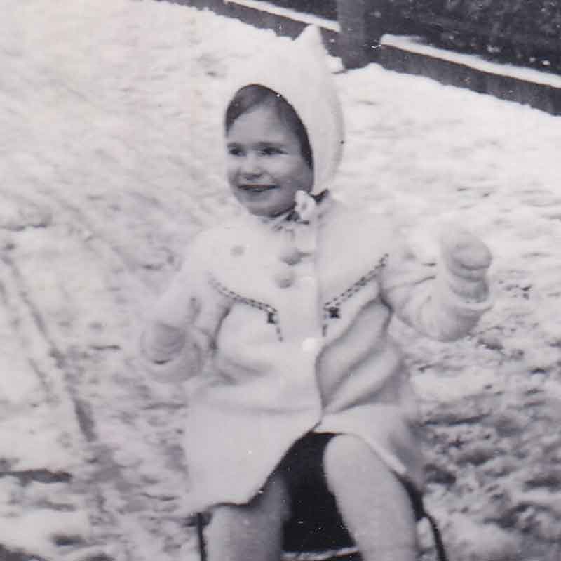 Paula as a toddler playing on a sled in Eindhoven before the war.