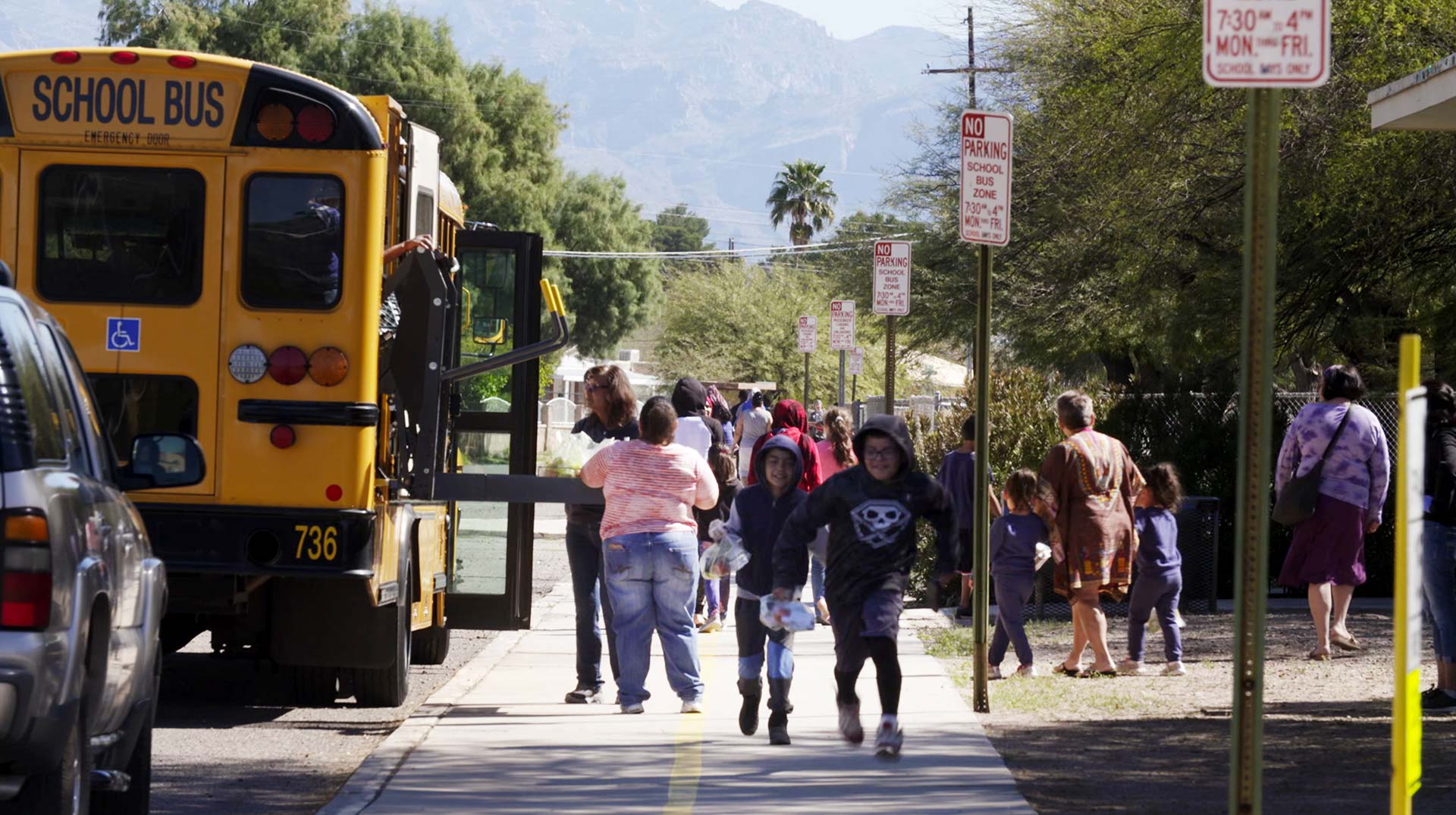 Students and families receive packaged meals from Tucson Unified School District workers who are distributing meals along the district's bus routes during closures associated with the COVID-19 pandemic. 