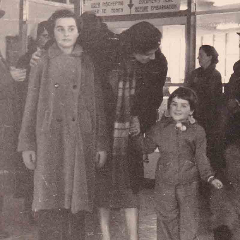 Departing Holland from Rotterdam Harbor in 1953 to emigrate to the United States. Bertie (left), age 10. Her Aunt Sary has an arm draped around her shoulder and is also holding the hand of Bertie’s sister Miriam. Her other sister, Rosecarrie, is a blur beside Miriam. Bertie’s mother is seated in the back, second from right. Bertie’s father is in the background, wearing a hat.