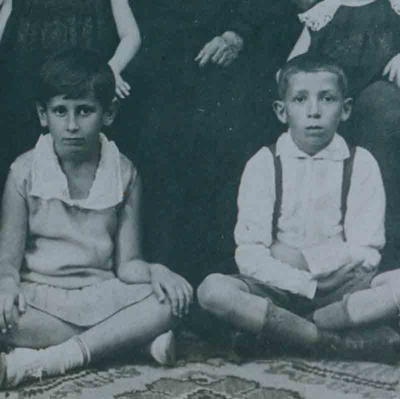 Family photo before the war with extended family. Yulia’s grandmother, Faina, is in the center. Yulia’s mother, Vera, is to the right of Faina, and beside her is Yulia’s father, Abraham. Yulia (left) and her twin sister, Yevgenia (right) are wearing matching black dresses.