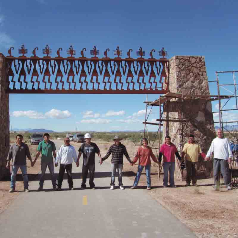 Chris’s public art installation 'Joining Hands,' near the Julian Wash greenway in Tucson, depicts her vision of community: people joining hands in friendship. She was inspired by a design on a 1,000-year-old Hohokam pot found in the area. Pictured are Chris, her husband Jean-Paul Bierny, and the crew of masons who installed the work.