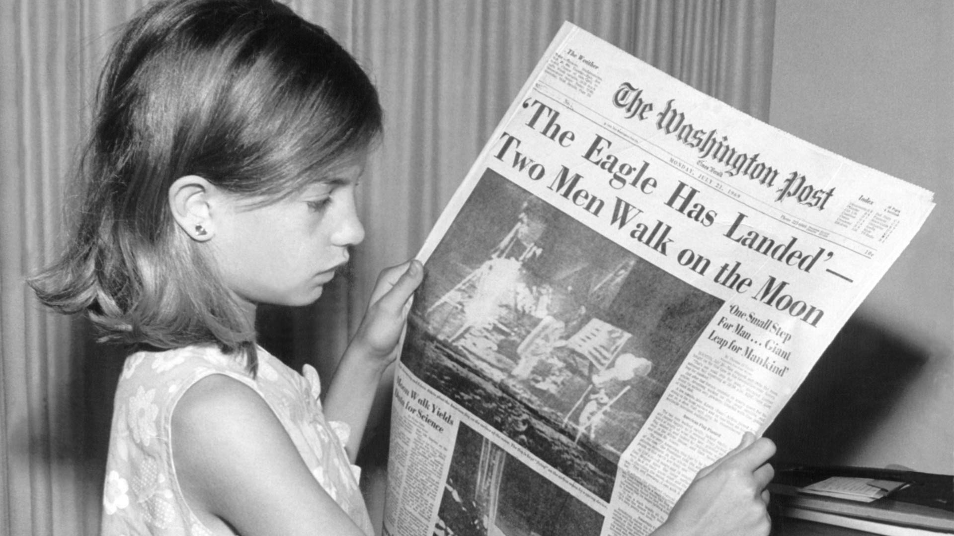 A young girl holding The Washington Post newspaper on Monday, July 21, 1969. The headline reads: 'The Eagle Has Landed. Two Men Walk on the Moon.'