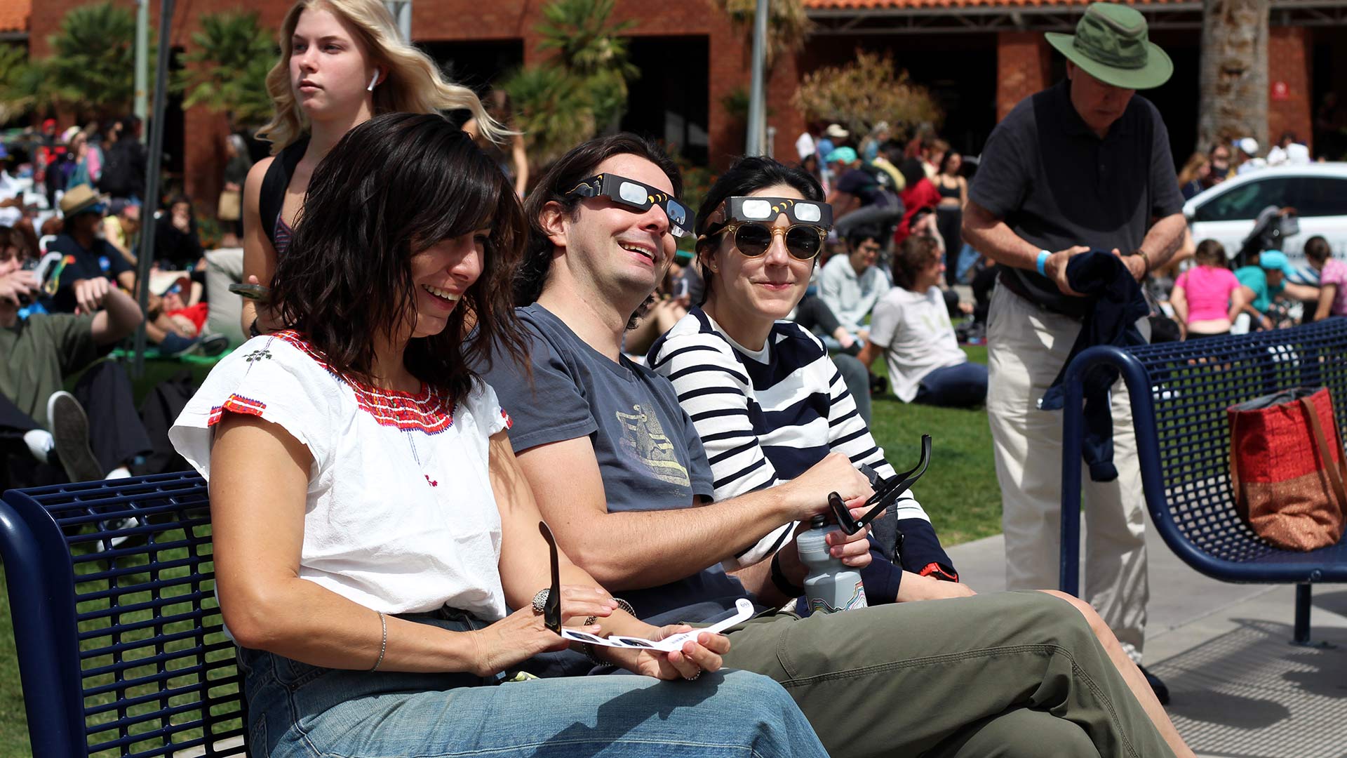 A group of three watch the solar eclipse in Tucson, Ariz., on Monday, April 8, on the University of Arizona campus mall. 