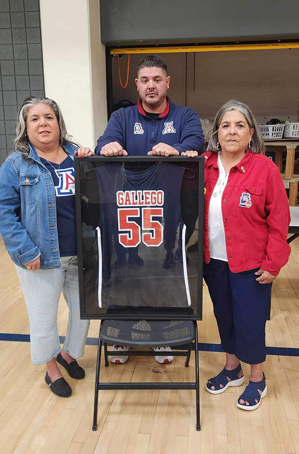 Rudy Gallego's son, also named Rudy, daughter Angela, and wife Sherry pose next to his jersey after the University of Arizona's wheelchair basketball program retired it.