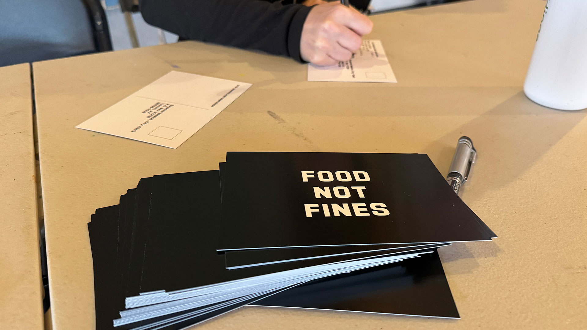 A woman writes a postcard to the Tucson Mayor and Council asking them to reconsider a city ordinance that requires a permit to distribute food to 10 or more people in city parks on Friday, March 15, 2024. 
