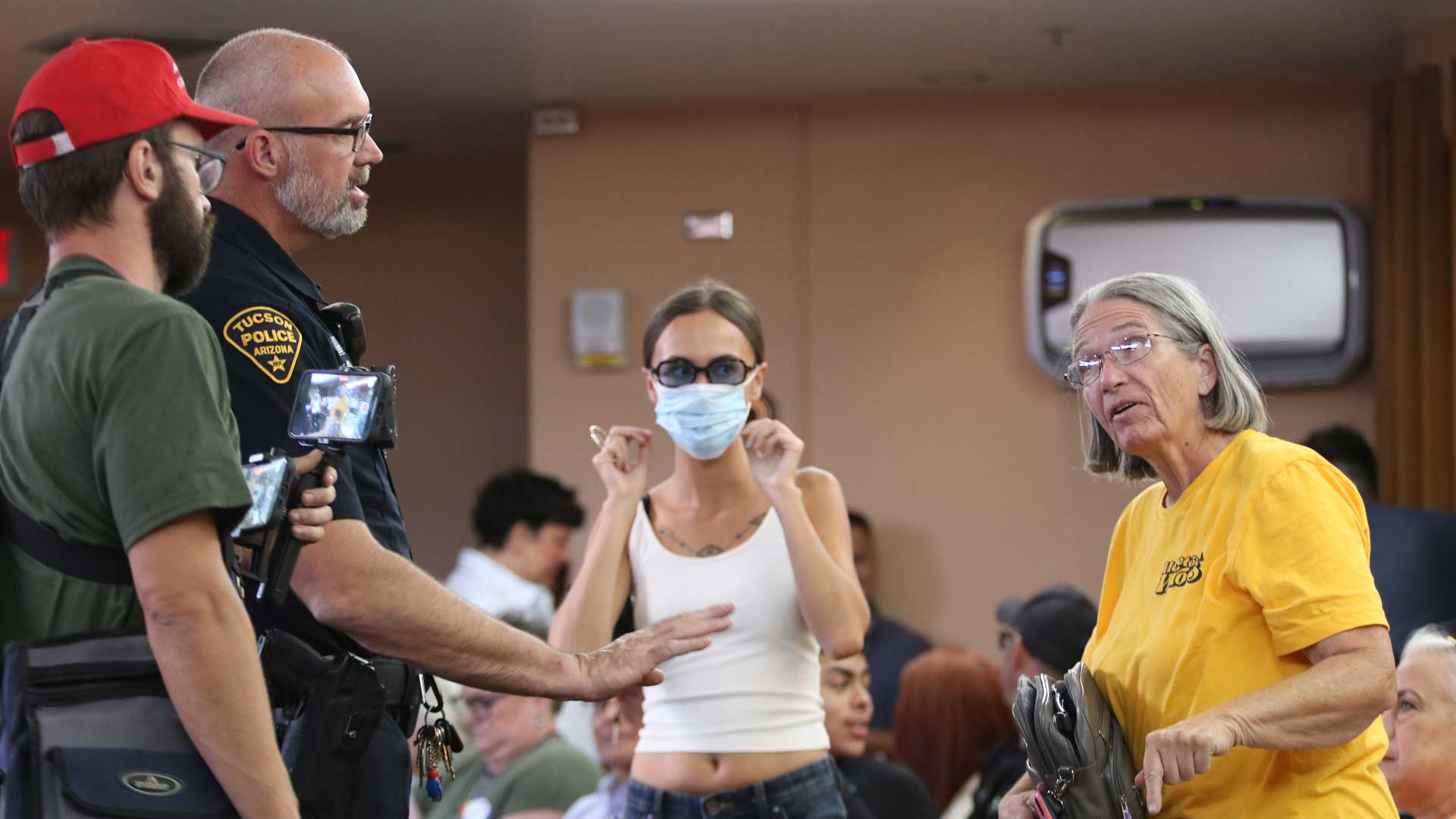 A heckler engages with another audience member as Tucson Police interjects the argument at a city council meeting on June 4. The man was eventually escorted out of the building after booing several proclamation decisions.