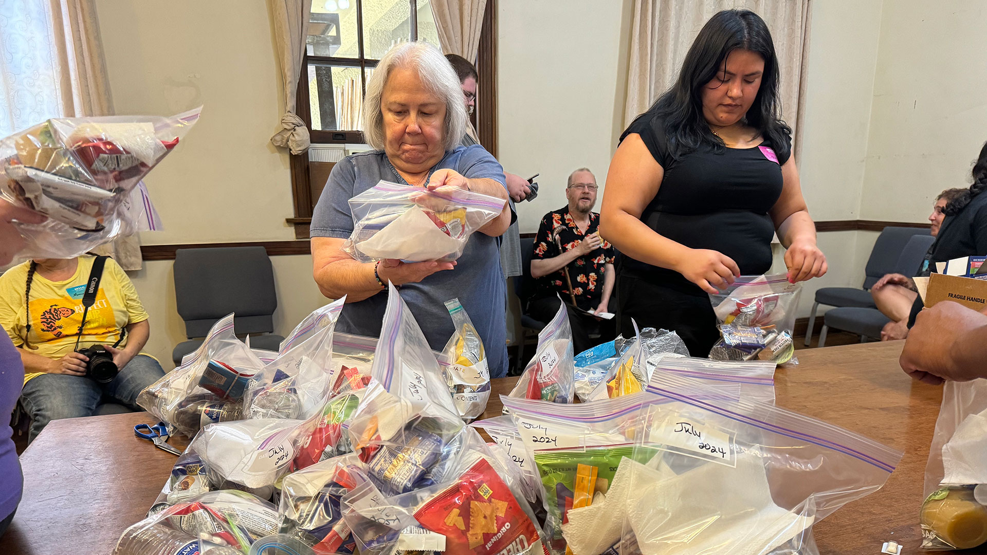Two volunteers pack bags of snacks to pass out to unhoused people in Tucson at the Historic Y on Sunday, July 22, 2024. 