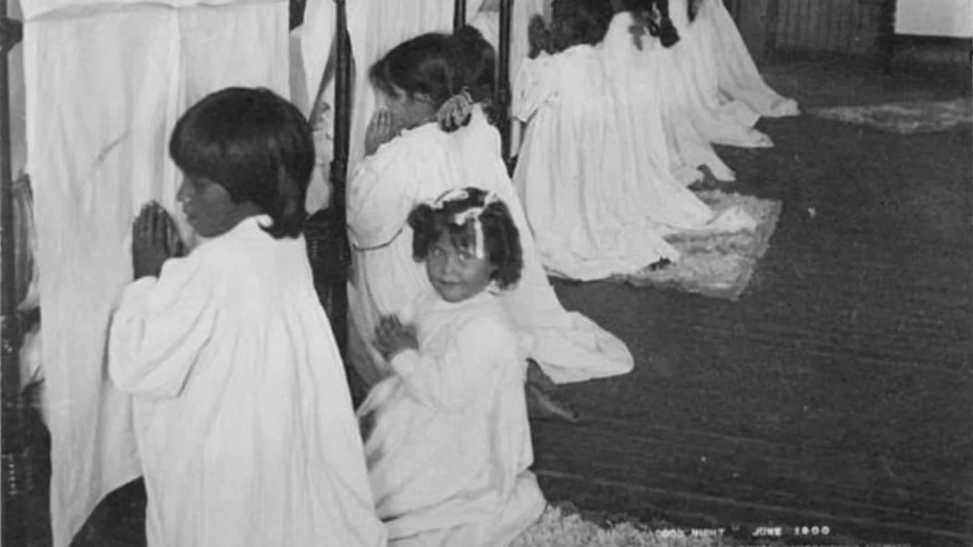 Students pray beside their beds at an Indian boarding school in Arizona, around 1900.