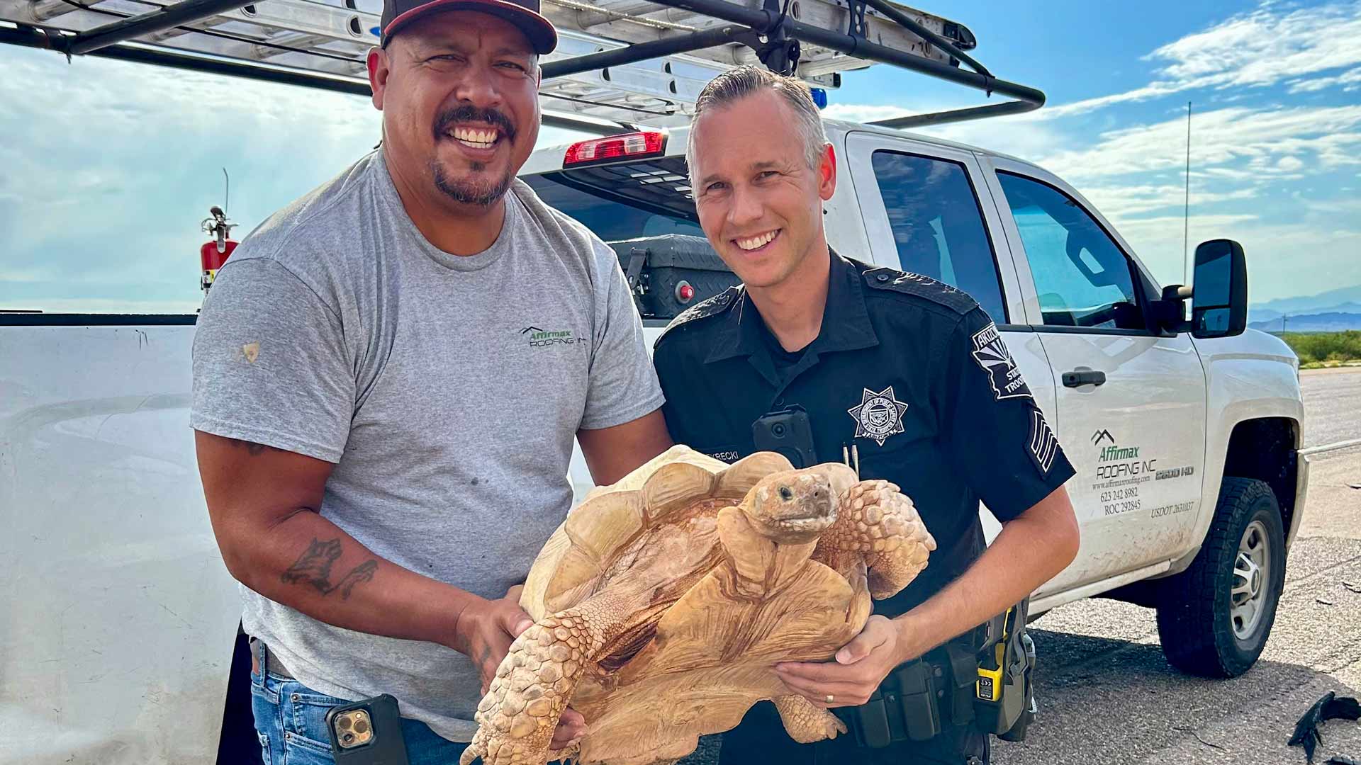 An unidentified driver and Arizona Department of Public Safety Sgt. Steven Sekrecki hold a rescued a sulcata tortoise that was attempting to cross Interstate 10 near Picacho, Ariz., on July 30, 2024. The motorist and Sekrecki managed to get the tortoise off the roadway unharmed. 