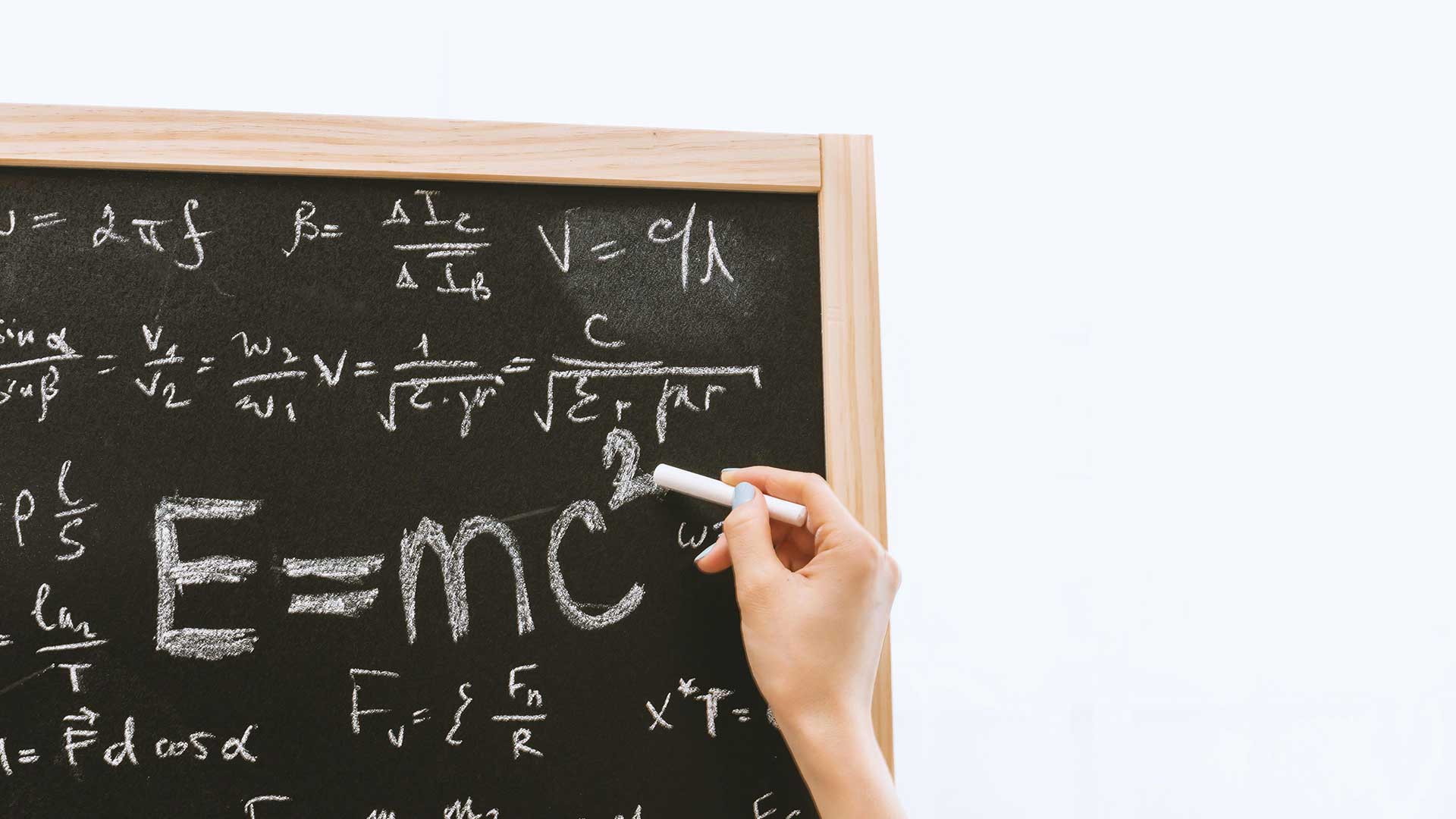 Person holding chalk in front of chalk board.
