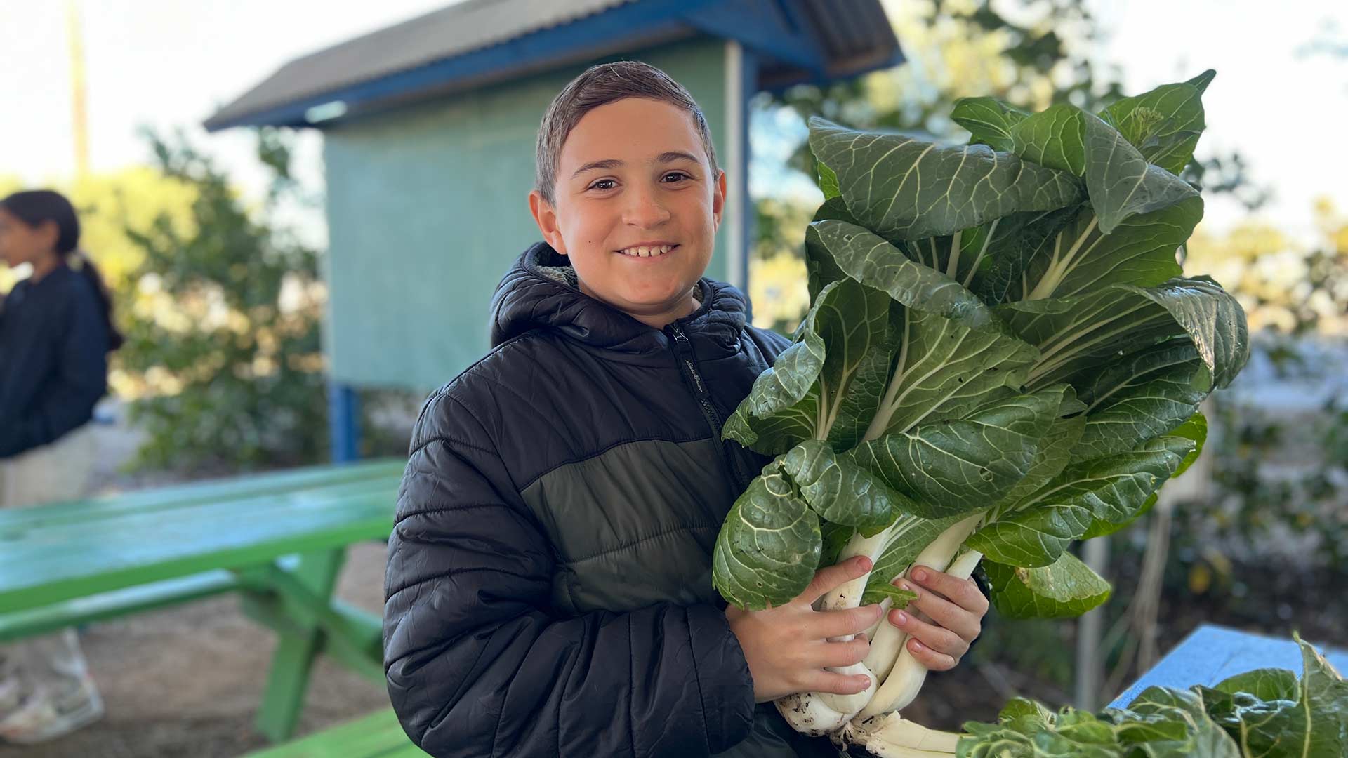 A student at Manzo Elementary School holds a bunch of harvested bok choy.
