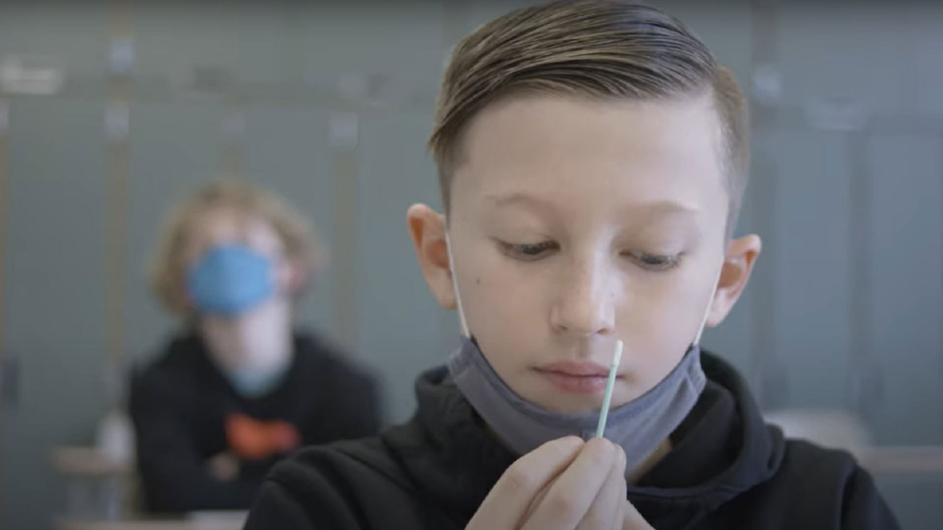 An elementary school student prepares to self-administer a COVID-19 test in a frame from a promotional video by Ginkgo Bioworks, which distributes "pooled testing" systems to schools around the country. 